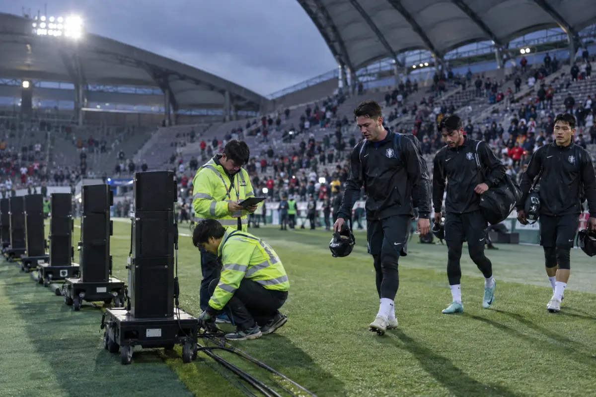 Match‑day speaker towers and technicians on the sideline at Seoul World Cup Stadium, 21 Sept — equipment now at the centre of a safety dispute.