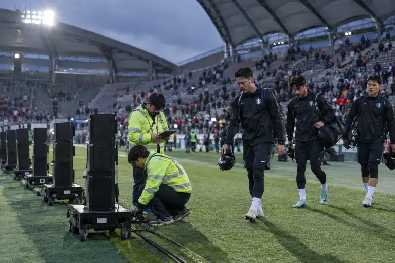 Match‑day speaker towers and technicians on the sideline at Seoul World Cup Stadium, 21 Sept — equipment now at the centre of a safety dispute.